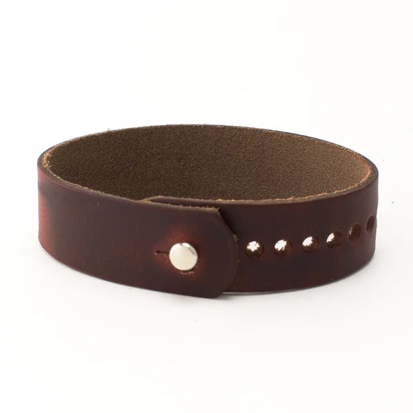 A dark brown leather cuff bracelet with a snap closure and row of holes, shown on a white background.